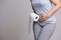 Woman hand holding her crotch lower abdomen and tissue or toilet paper roll. Disorder, Diarrhea, incontinence. Healthcare concept