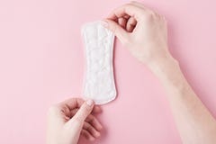 Woman hands hold sanitary pad on a pink background stock photography Woman hands hold sanitary pad on a pink background stock photography