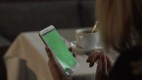 Woman hands touching on green screen mobile phone on background coffee cup stock footage Woman hands touching on green screen mobile phone on background coffee cup stock footage