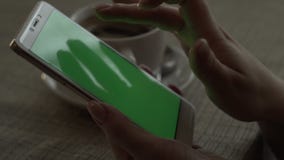 Woman hands touching on green screen mobile phone on background coffee cup stock footage Woman hands touching on green screen mobile phone on background coffee cup stock footage