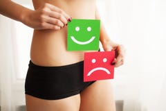 Woman Health Problem. Closeup Of Female With Fit Slim Body In Panties Holding Two Card With Sad Smiley And Happy Face