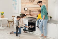 Woman and her family taking out tray with baked cookies stock images Woman and her family taking out tray with baked cookies stock images