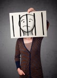 Woman holding a paper with a prisoner behind the bars on it in f Royalty Free Stock Image Woman holding a paper with a prisoner behind the bars on it in f Royalty Free Stock Image