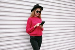 Woman holding smartphone in colorful pink knitted sweater stock image Woman holding smartphone in colorful pink knitted sweater stock image