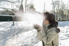 A woman holds a handful of snow in her hands and blows on it. Wi stock photography A woman holds a handful of snow in her hands and blows on it. Wi stock photography
