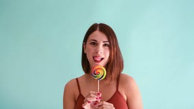 Woman licks her lips next to lollipop