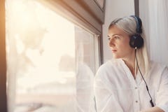 Woman listening to music, looking through the window royalty free stock photography Woman listening to music, looking through the window royalty free stock photography