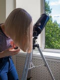 Woman looks through a window into a telescope royalty free stock photo Woman looks through a window into a telescope royalty free stock photo