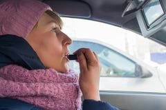 Woman paints her lips with lipstick in the car stock photo Woman paints her lips with lipstick in the car stock photo