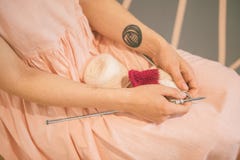 Woman in pink dress put knitting needles on her knees. Warm cozy colors mood stock image Woman in pink dress put knitting needles on her knees. Warm cozy colors mood stock image