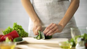 Woman preparing salad at the kitchen, female hands cutting cucumber, dieting stock photography Woman preparing salad at the kitchen, female hands cutting cucumber, dieting stock photography
