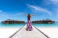 Woman with raised hands on bridge on beach in Maldives