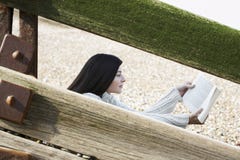 Woman Reading Book While Sitting Behind Balustrade At Beach royalty free stock image Woman Reading Book While Sitting Behind Balustrade At Beach royalty free stock image