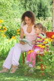 Woman Reads Book To Little Girl In Garden Stock Photos