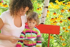 Woman Reads Book To Little Girl In Garden Stock Images