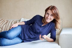 Woman relaxing in living room holding remote control and watching television or tv stock image Woman relaxing in living room holding remote control and watching television or tv stock image