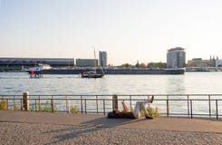Woman resting lying on the Amstel River shore against the backdrop of the port and Central Station in Amsterdam royalty free stock photography Woman resting lying on the Amstel River shore against the backdrop of the port and Central Station in Amsterdam royalty free stock photography