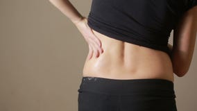 Woman rubs cream loin. back pain. muscle pain
