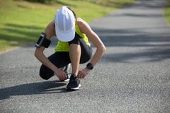 Woman runner tying shoelace at tropical park Stock Photo Woman runner tying shoelace at tropical park Stock Photo