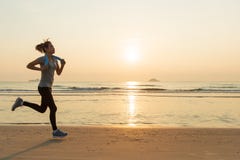 Woman Running On Beach At Sunrise Stock Photo