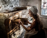 Woman in a rustic dress sitting next to old stove in a ruined abandoned house royalty free stock photo Woman in a rustic dress sitting next to old stove in a ruined abandoned house royalty free stock photo