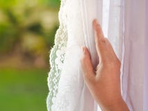Woman`s hand opening curtains in the bedroom with natural light stock image Woman`s hand opening curtains in the bedroom with natural light stock image