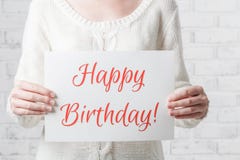Woman with a sign in her hands with the words happy birthday
