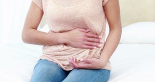 Woman sitting on bed with stomach pain