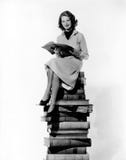 Woman sitting on pile of books