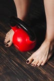 Woman standing bare foot with red kettlebell between her legs Royalty Free Stock Photos Woman standing bare foot with red kettlebell between her legs Royalty Free Stock Photos