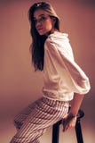 Woman in striped pants sitting on wooden chair. In studio at sunset Stock Photography Woman in striped pants sitting on wooden chair. In studio at sunset Stock Photography