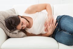 Woman suffering from stomachache on sofa