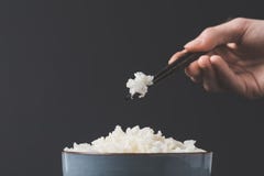 Woman taking freshly cooked rice from bowl with chopsticks Stock Photos Woman taking freshly cooked rice from bowl with chopsticks Stock Photos