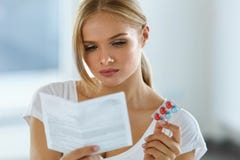 Woman Taking Medicine. Female With Pills Reading Instructions Stock Photo Woman Taking Medicine. Female With Pills Reading Instructions Stock Photo