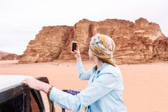 Woman tourist shoots video or photo on mobile phone of the Jordanian desert stock photo Woman tourist shoots video or photo on mobile phone of the Jordanian desert stock photo