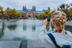 Woman Tourist Taking Photo Of The Rijksmuseum In Amsterdam On The Mobile Phone. Travel In Europe City Trip Concept Royalty Free Stock Images Woman Tourist Taking Photo Of The Rijksmuseum In Amsterdam On The Mobile Phone. Travel In Europe City Trip Concept Royalty Free Stock Images
