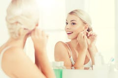 Woman trying on earring looking at bathroom mirror stock photo Woman trying on earring looking at bathroom mirror stock photo