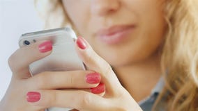 Hands of a young woman with a mobile phone, smiling lips slightly blurred stock video Hands of a young woman with a mobile phone, smiling lips slightly blurred stock video