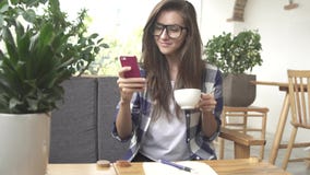 Woman using app on smartphone in cafe drinking coffee and laugh