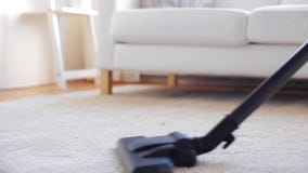 Woman with vacuum cleaner cleaning carpet at home