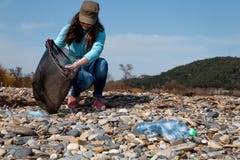 Woman volunteer helps clean the beach of plastic garbage. Earth day and environmental improvement concept. Stone coast on the stock images Woman volunteer helps clean the beach of plastic garbage. Earth day and environmental improvement concept. Stone coast on the stock images
