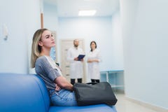 Woman waiting at a hospital hallway for a test results. Feeling nervous. Doctors talking on a background. royalty free stock photo Woman waiting at a hospital hallway for a test results. Feeling nervous. Doctors talking on a background. royalty free stock photo