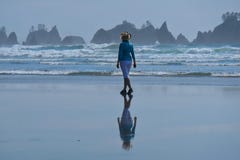 Woman walking on beach with scenic views of sea stacks. stock photo Woman walking on beach with scenic views of sea stacks. stock photo