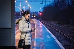 A woman is wating for a train and uses a smartphone at a railway royalty free stock images A woman is wating for a train and uses a smartphone at a railway royalty free stock images