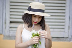 Woman Wearing Beige Sun Hat and White Sleeveless Top Holding White Flowers Stock Image Woman Wearing Beige Sun Hat and White Sleeveless Top Holding White Flowers Stock Image