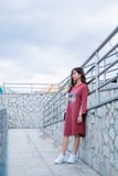 Woman Wearing Red Long-sleeved Shirt Dress Stands Next to Gray Metal Handrails stock photo Woman Wearing Red Long-sleeved Shirt Dress Stands Next to Gray Metal Handrails stock photo
