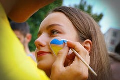 Woman with yellow-blue heart on her cheek