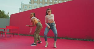 Women dancing together outdoors on street. Two young beautiful girls performers showing energetic sexy dance outside