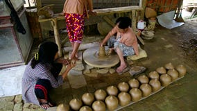 Women work with large wheel and talk in pottery workshop