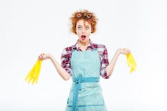 Wondered housewife holding yellow gloves in both hands